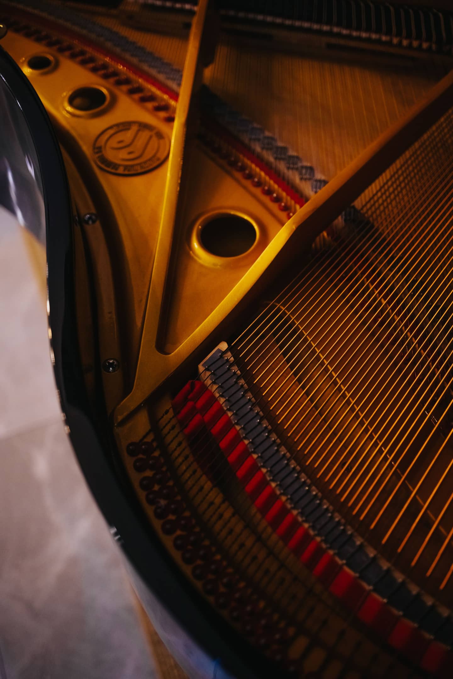 Inside a grand piano: the gold cast-iron plate, strings and tuning pins under warm light